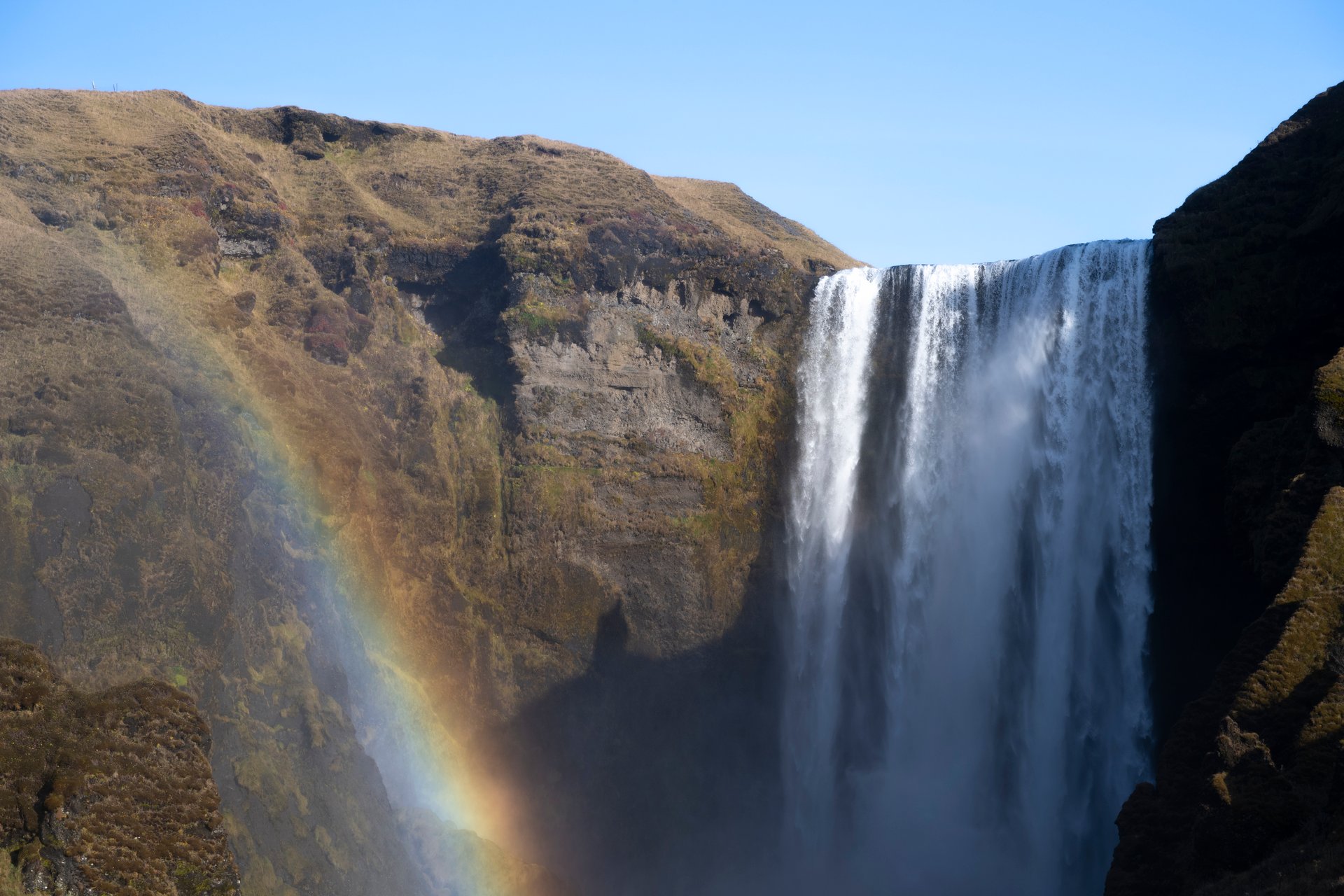 Skógafoss waterfall with rainbow forming in the spray