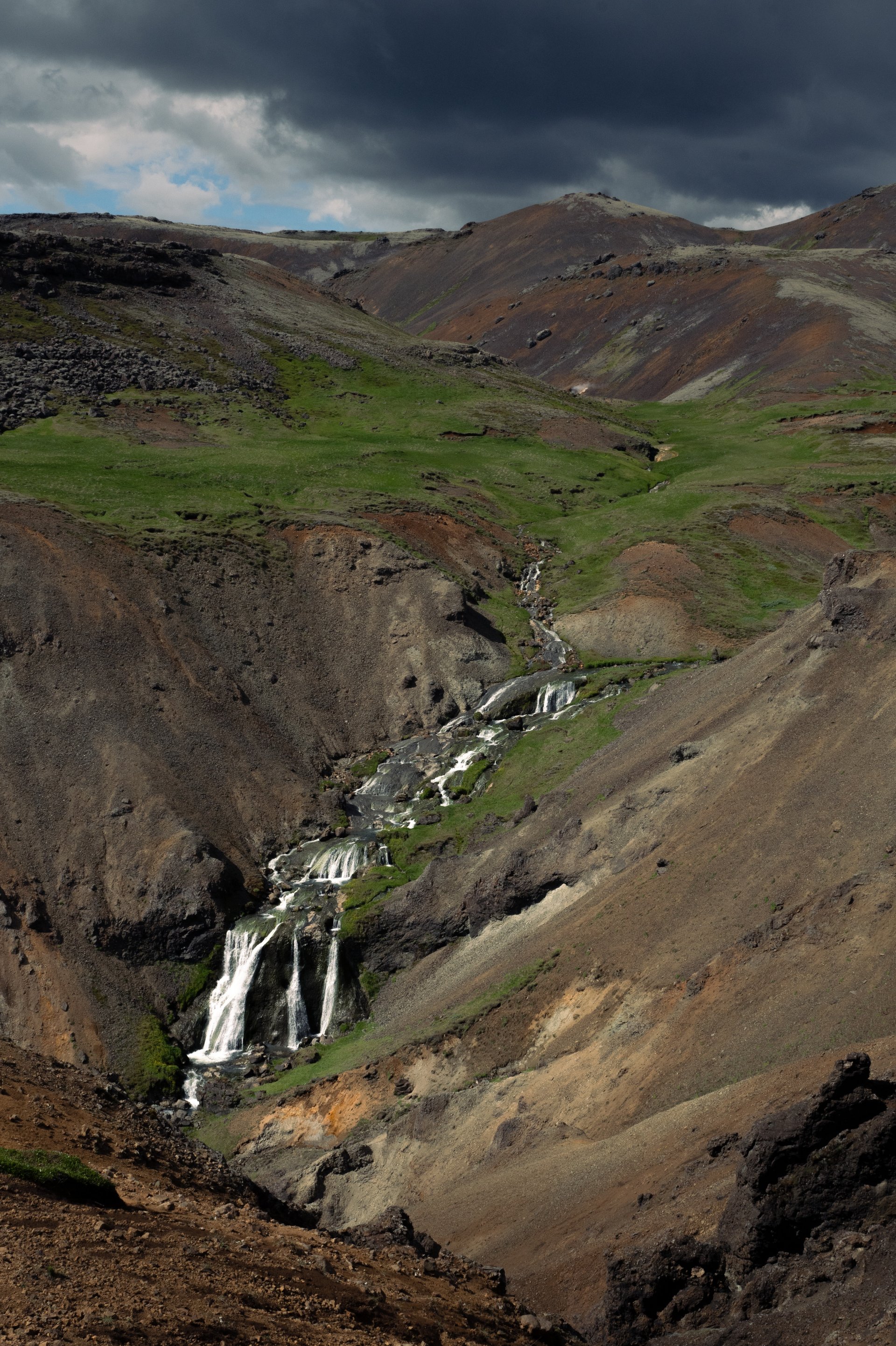 People relaxing in the warm Reykjadalur hot spring river surrounded by mountains
