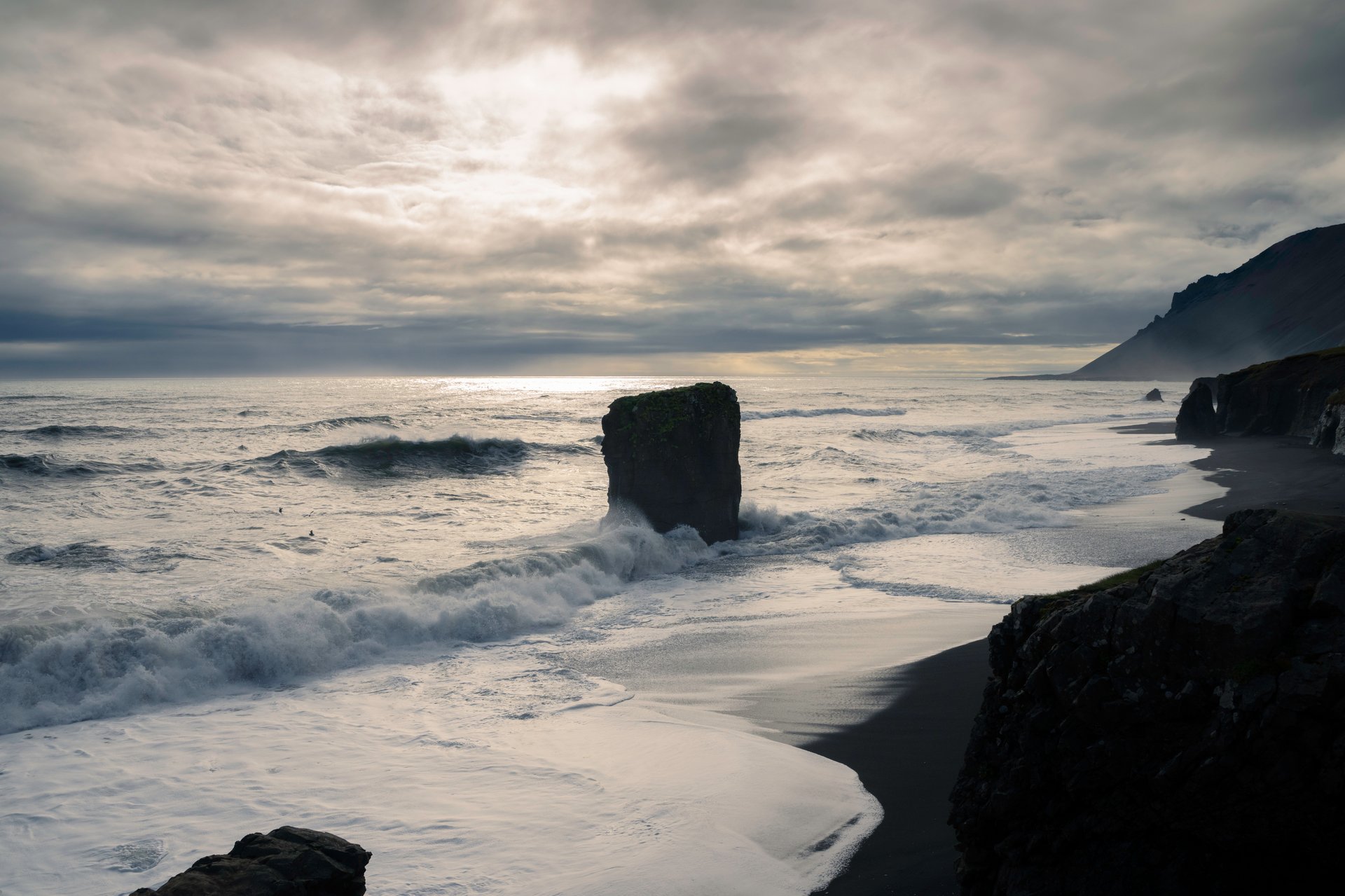Fauskasandur hidden black sand beach with sea stack and lava boulders