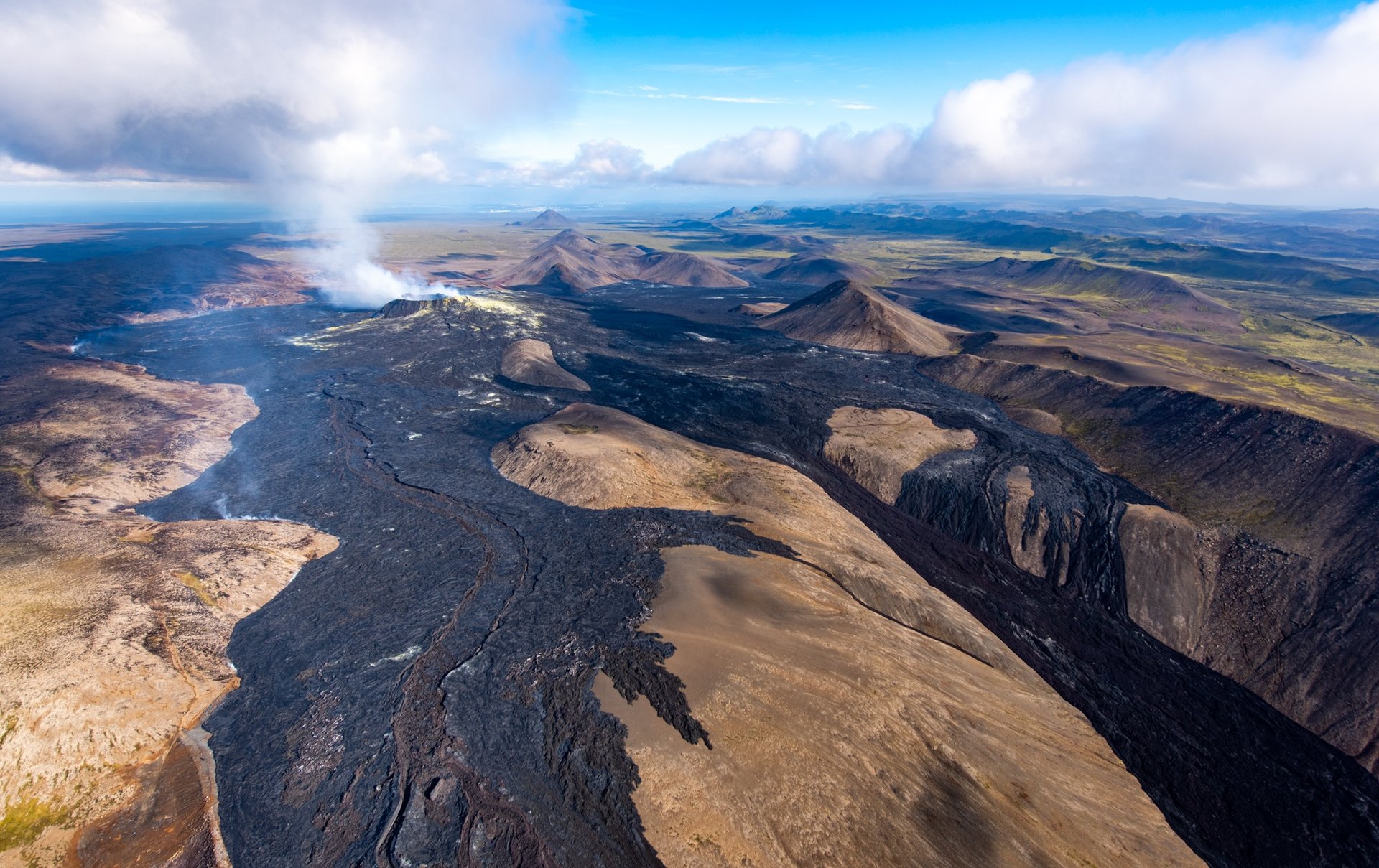 Helicopter flying over active volcanic eruption site with fresh lava flows on Reykjanes Peninsula