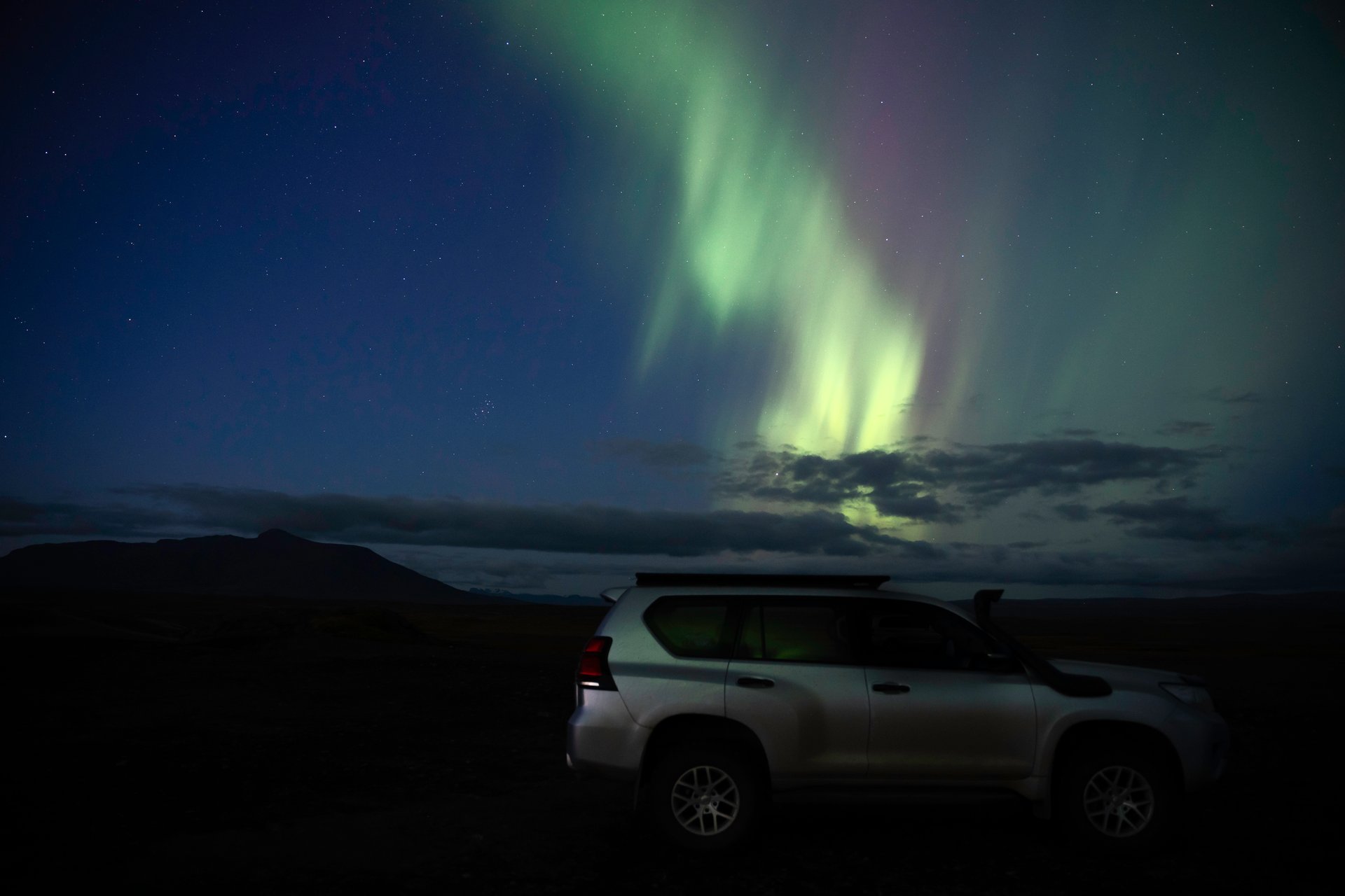 Northern Lights over the Land Cruiser during a private tour
