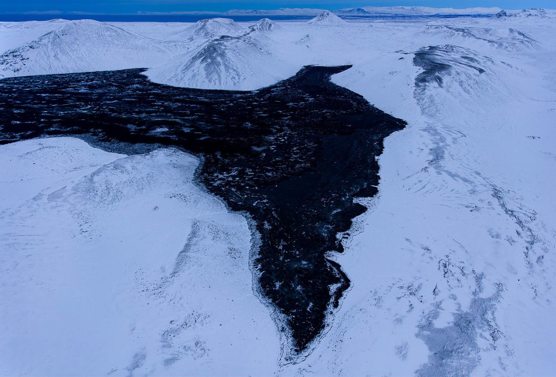 Active volcanic eruption with glowing lava from helicopter view
