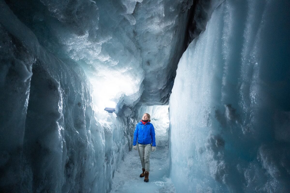 Visitor exploring illuminated ice cave passage