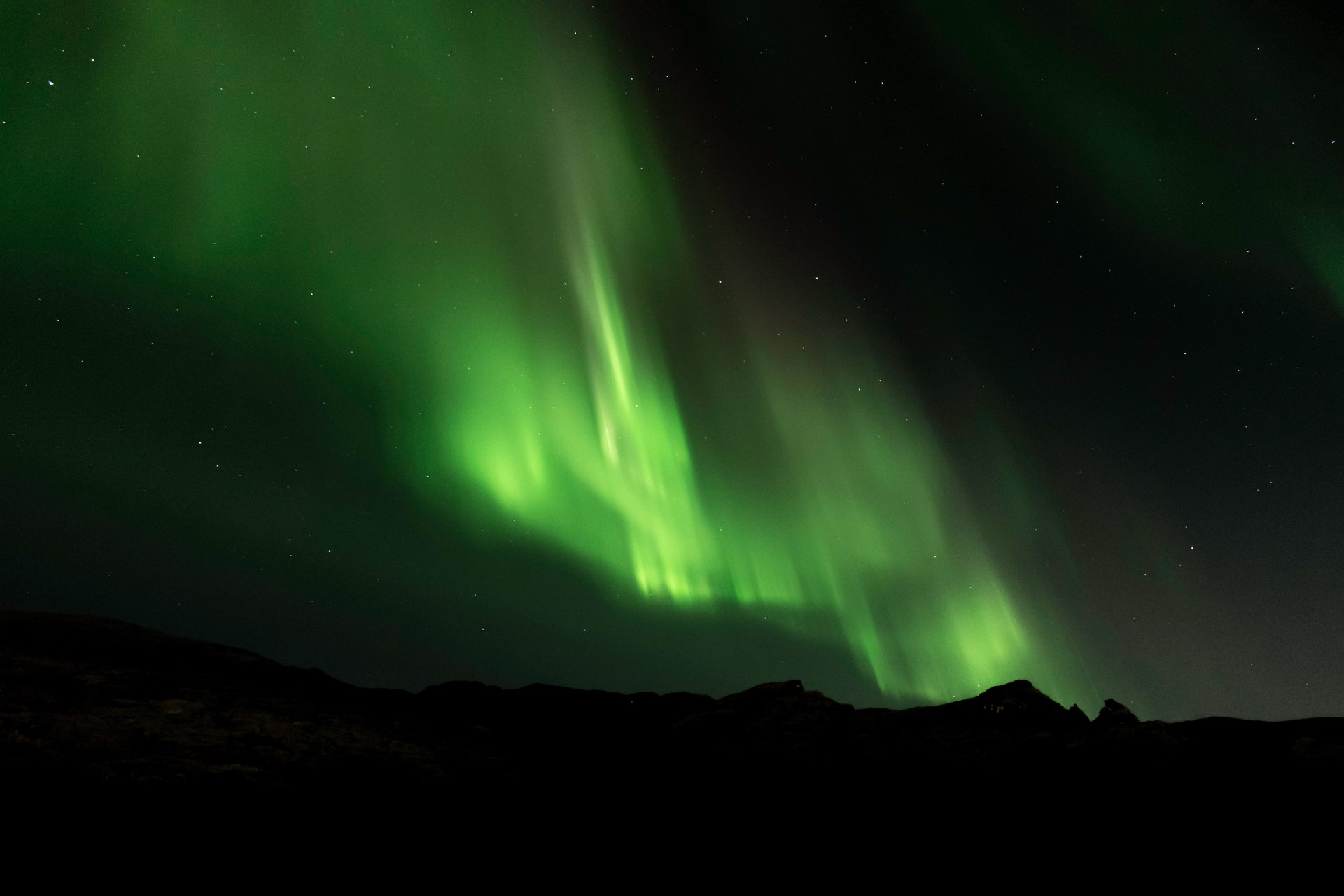 Expert guide leading intimate aurora hunting group under dancing Northern Lights