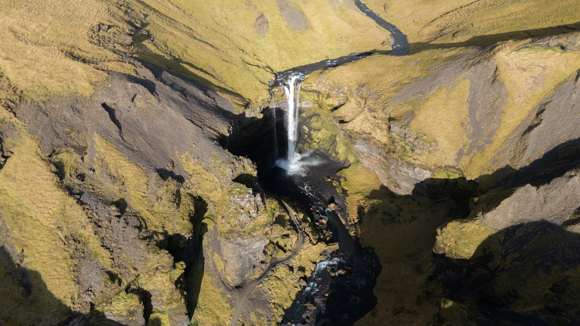 Kvernufoss waterfall with path leading behind the cascade