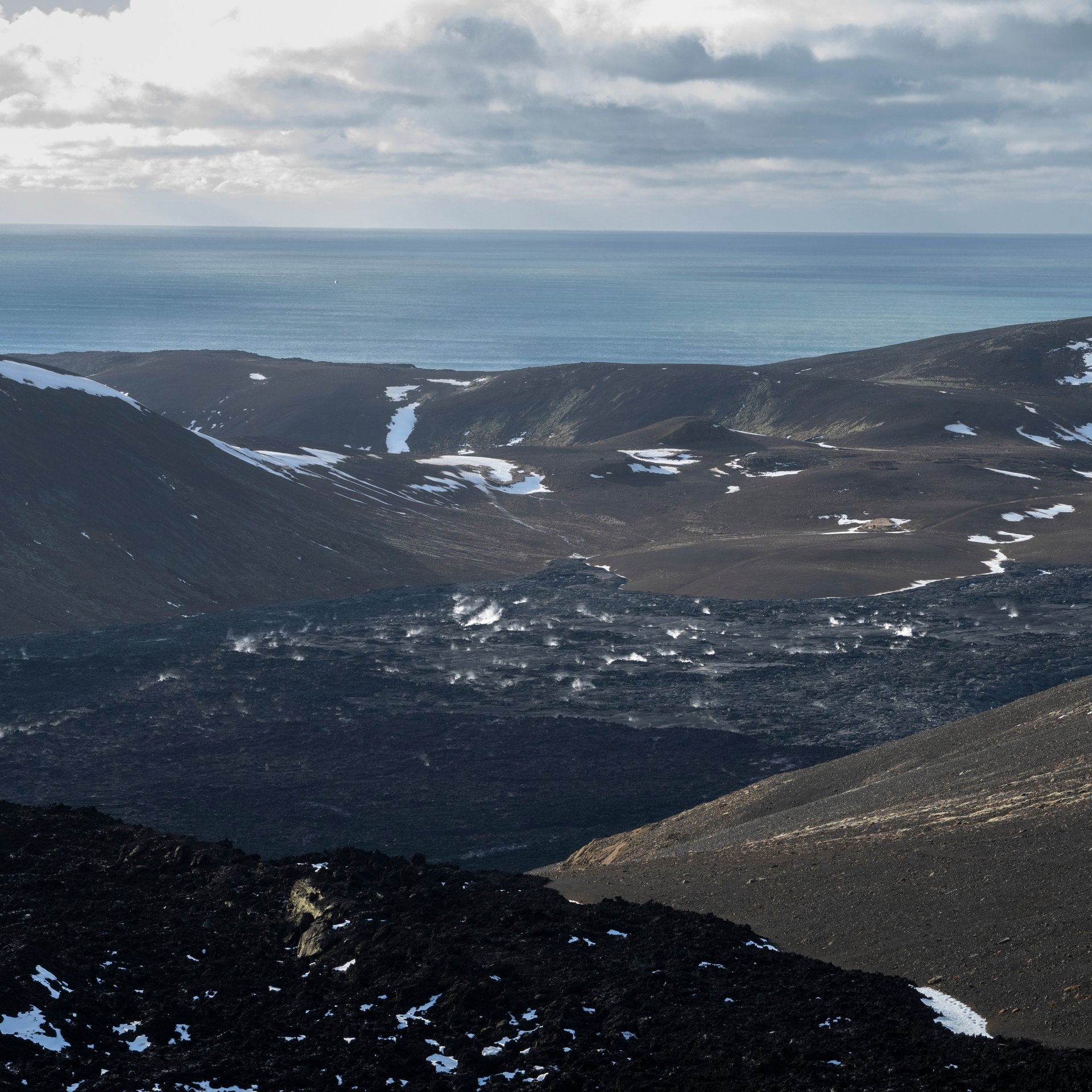 Vast lava fields stretching toward the ocean from the eruption site