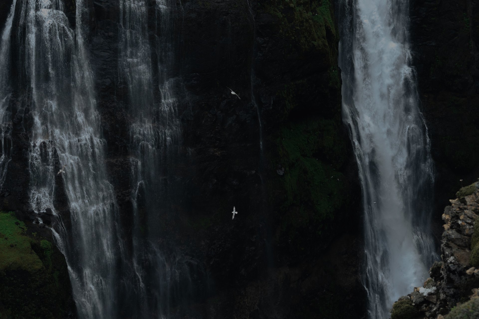 Hikers crossing river on their way to Iceland's majestic Glymur waterfall with dramatic canyon views