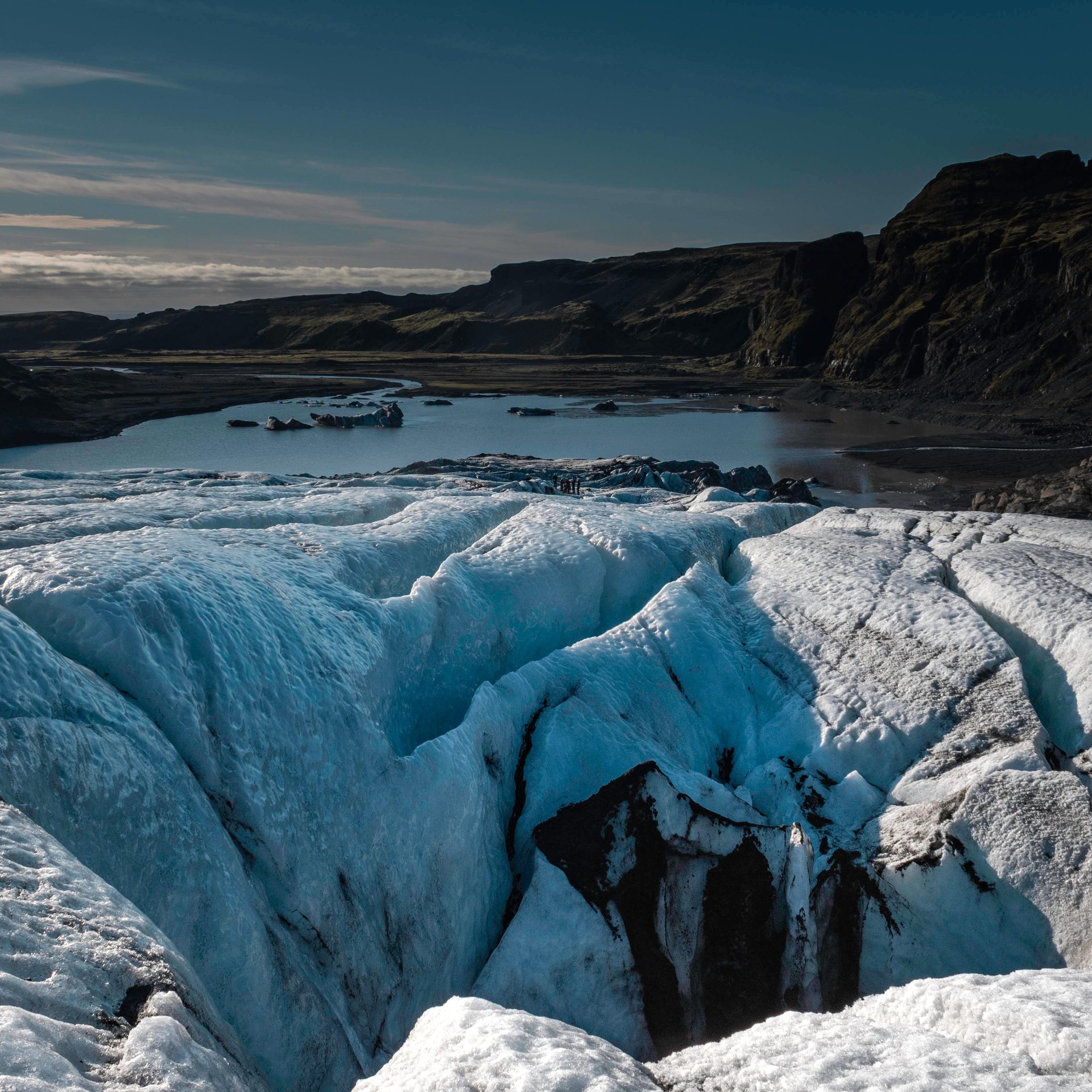 Glacier guides preparing equipment at Sólheimajökull glacier base with ice formations in background