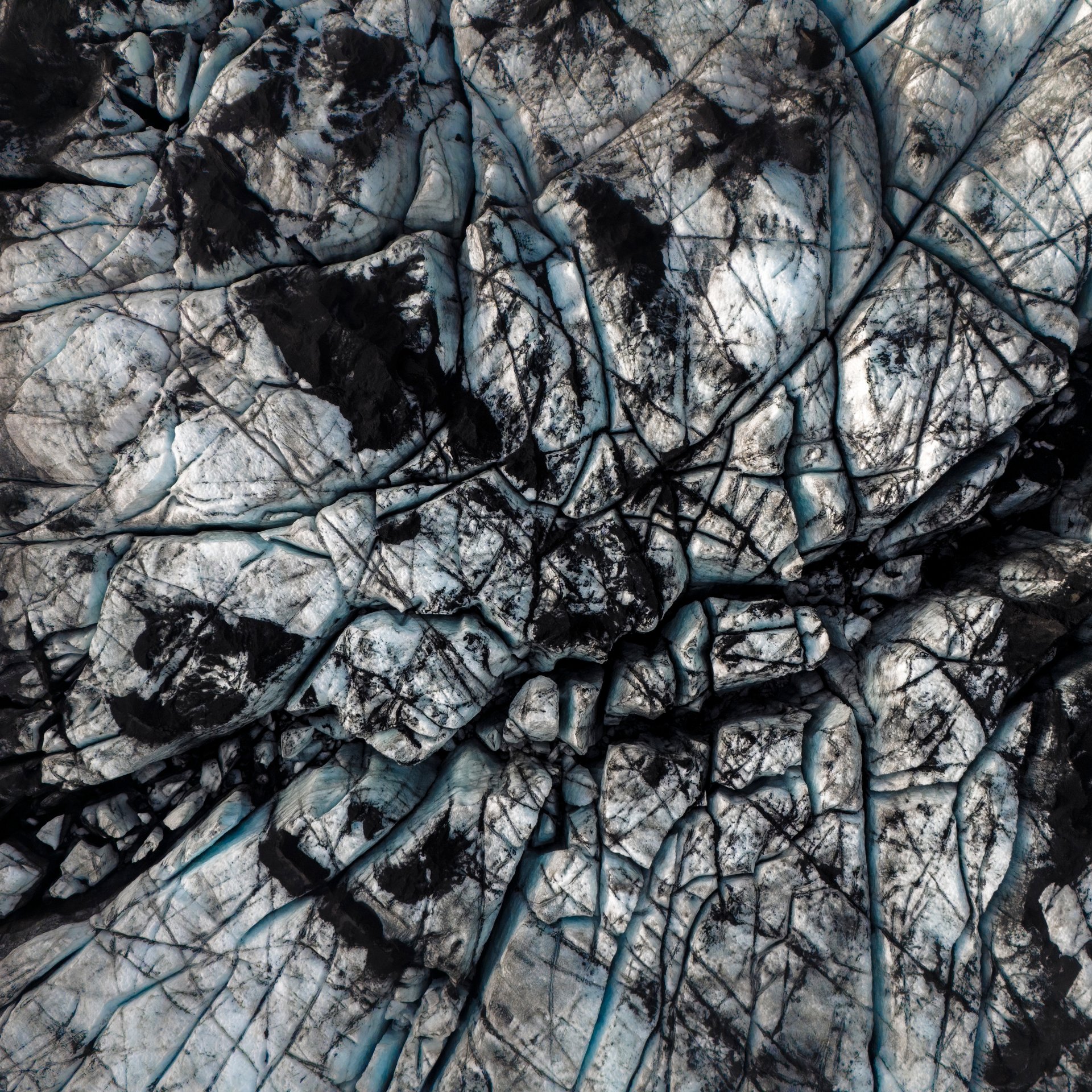 Hikers with crampons exploring deep blue crevasses and ice formations on Sólheimajökull glacier