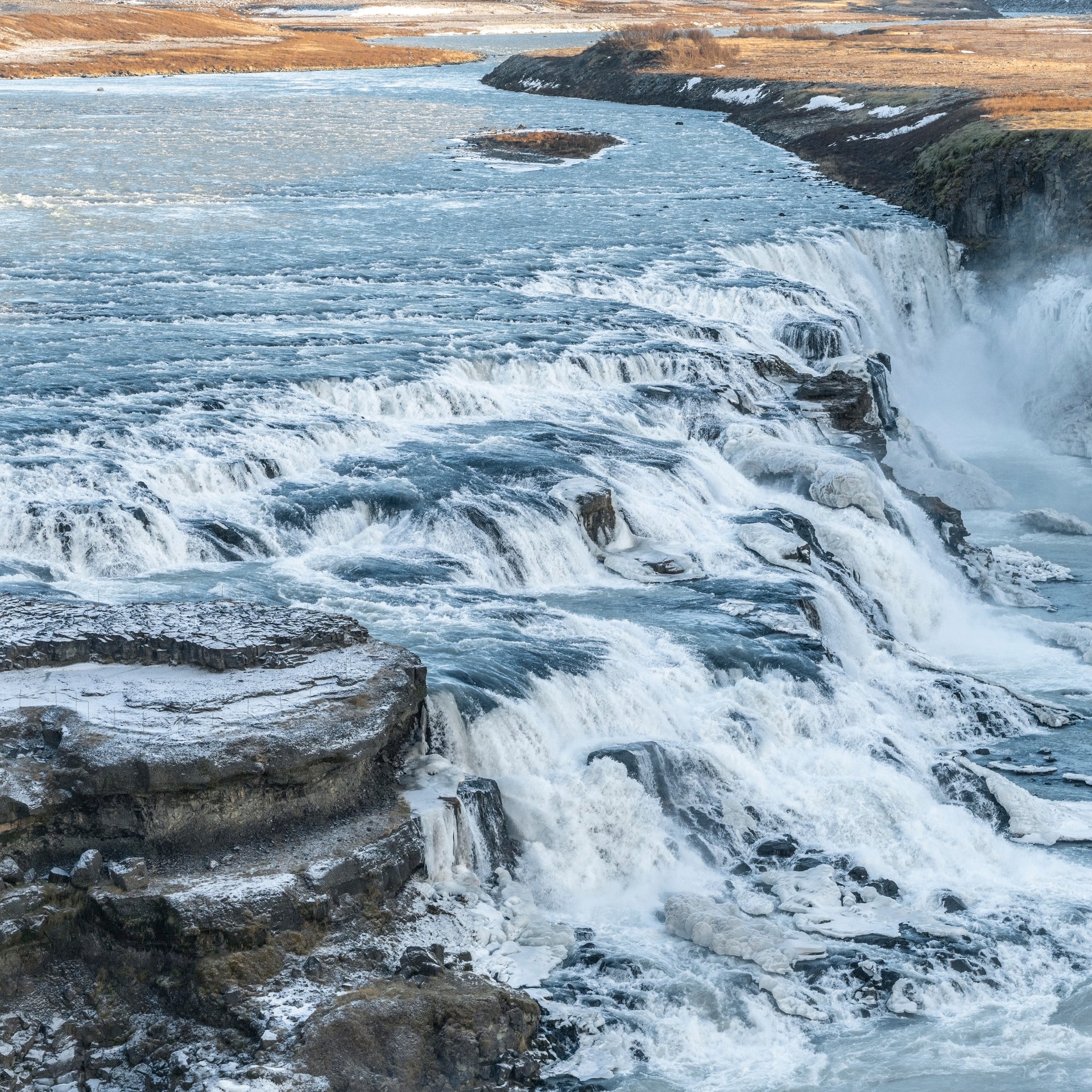 Magnificent Gullfoss waterfall with golden mist and rainbow in dramatic canyon setting