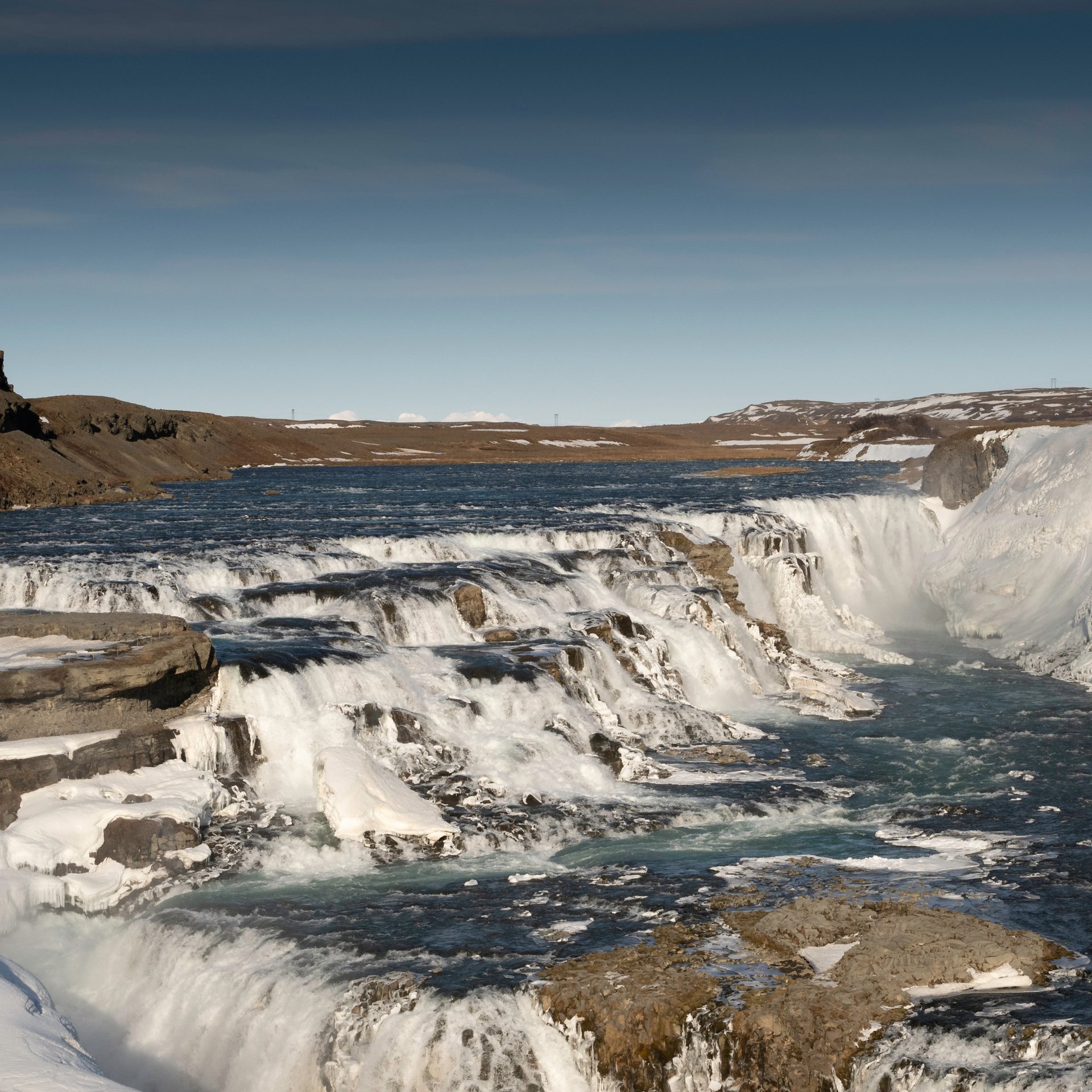 Powerful Gullfoss waterfall cascading down rocky cliffs with golden mist