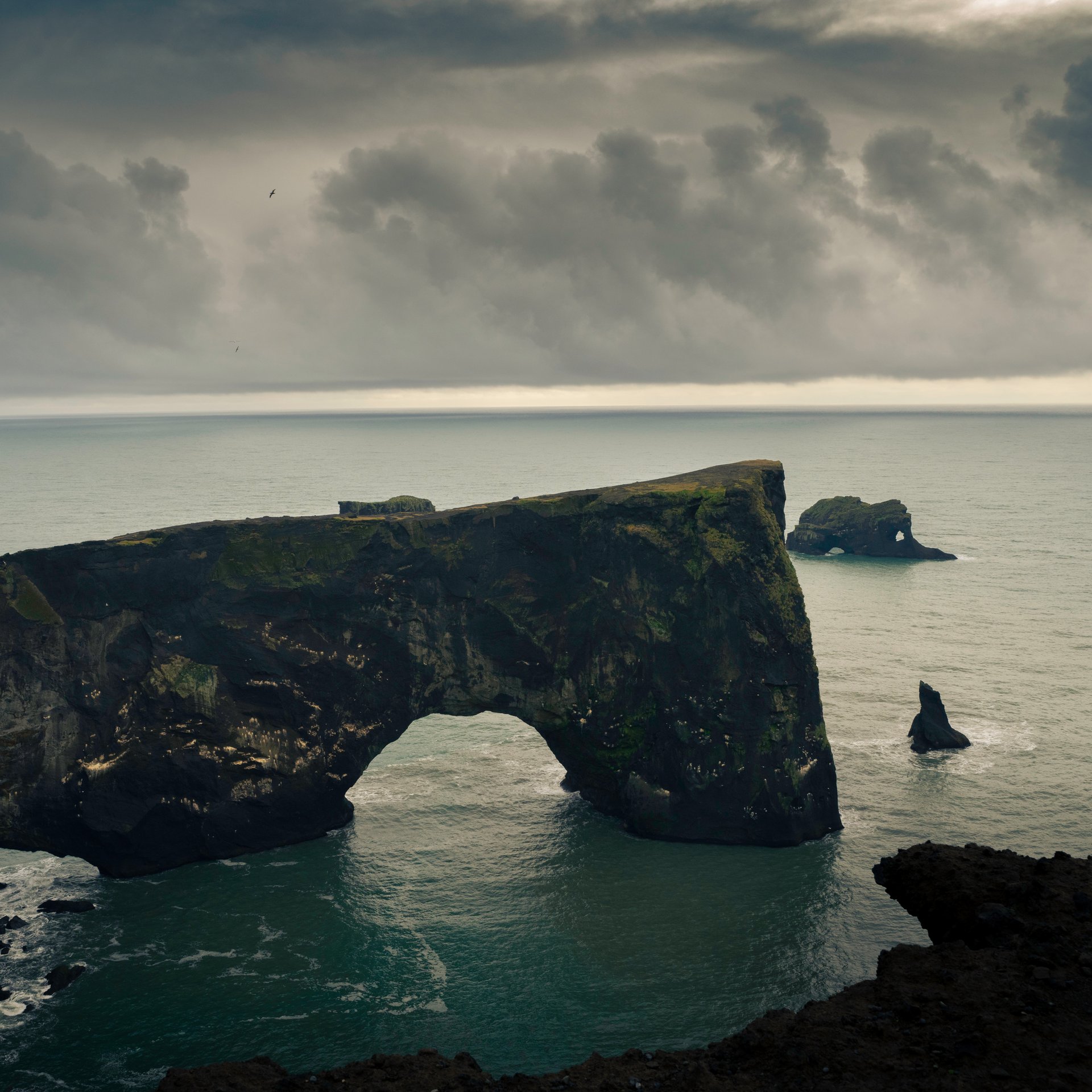 Spectacular Dýrhólaey natural arch towering above black sand coastline with ocean views