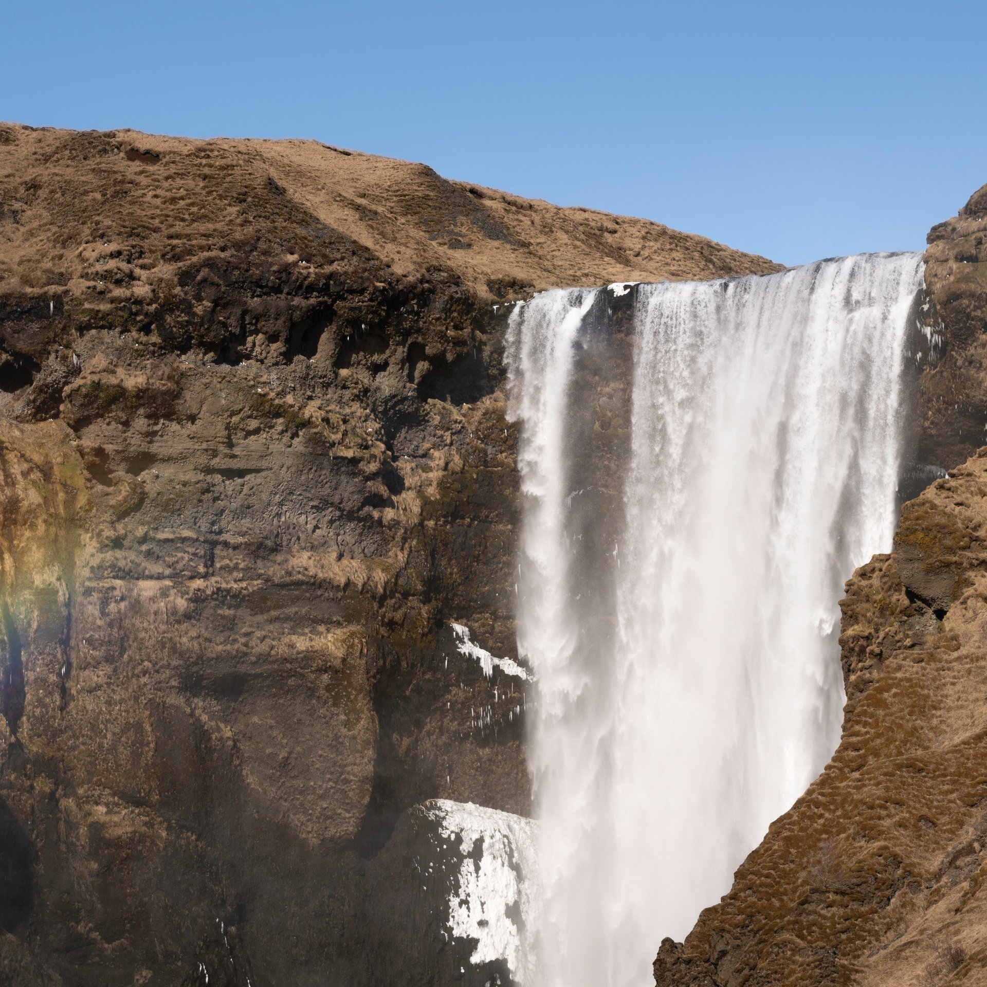Powerful Skógafoss waterfall with rainbow mist and dramatic cliffs