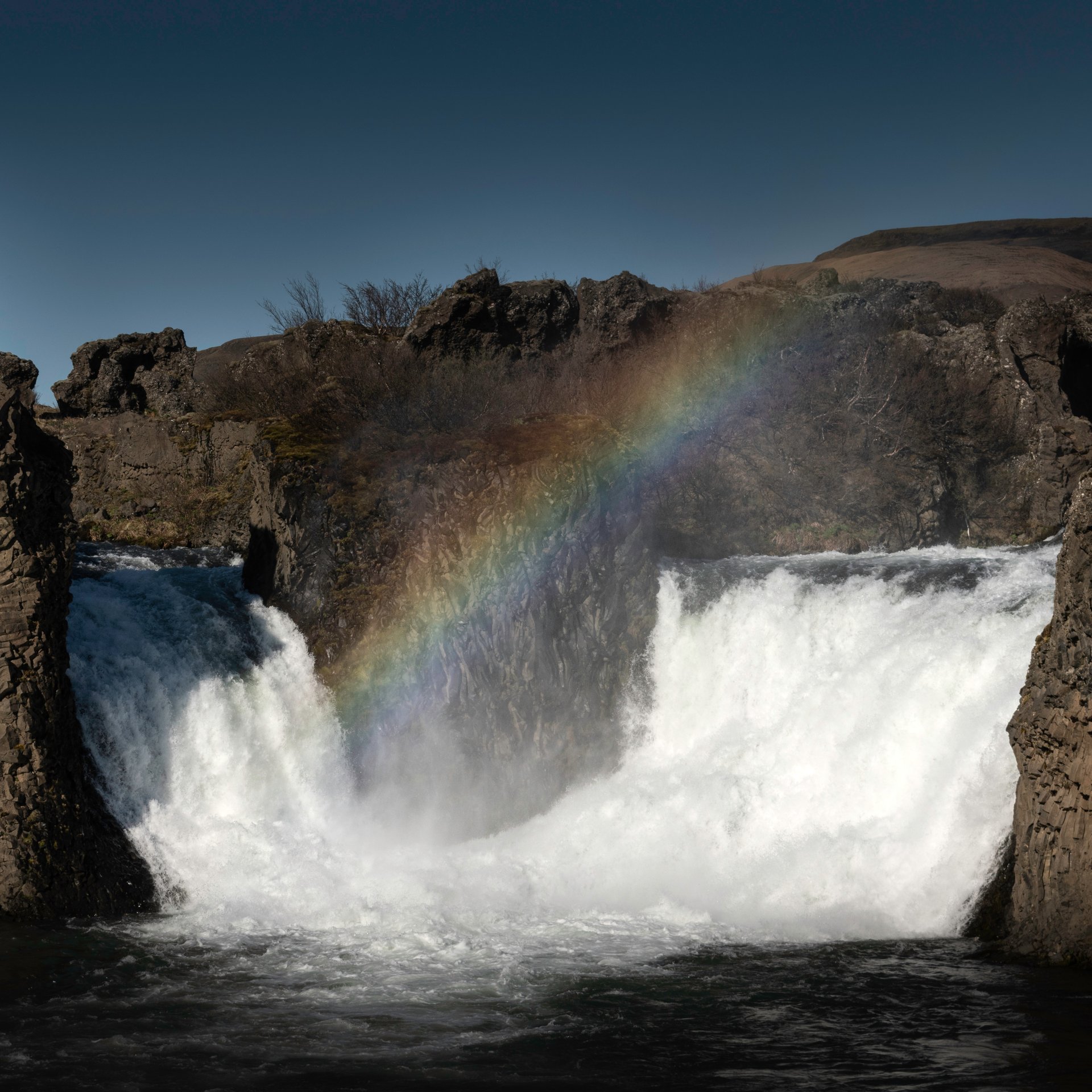 Hjálparfoss twin waterfalls cascading through distinctive hexagonal basalt column formations