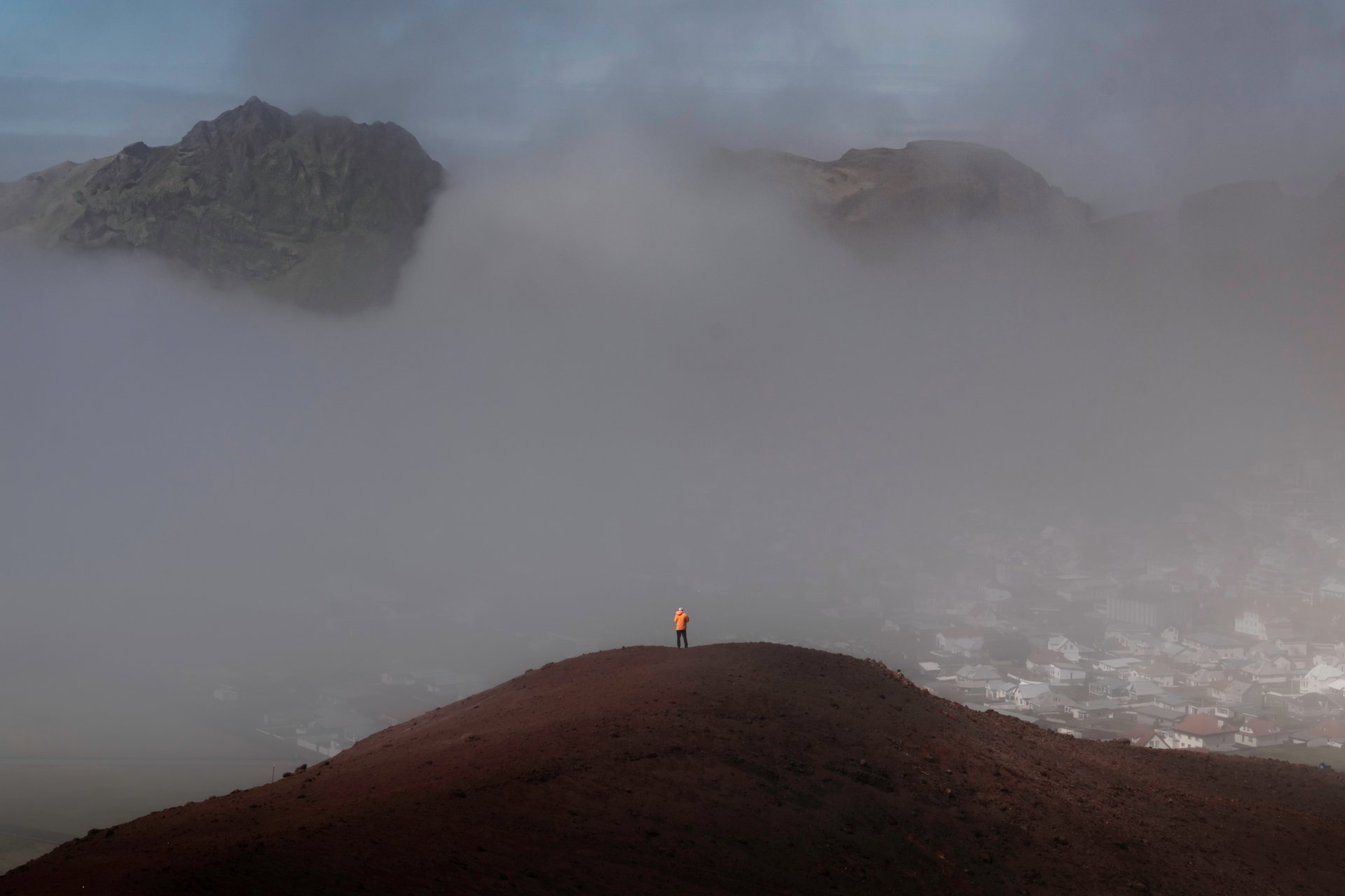 Hikers ascending Eldfell volcano crater with panoramic views over Heimaey and volcanic landscape