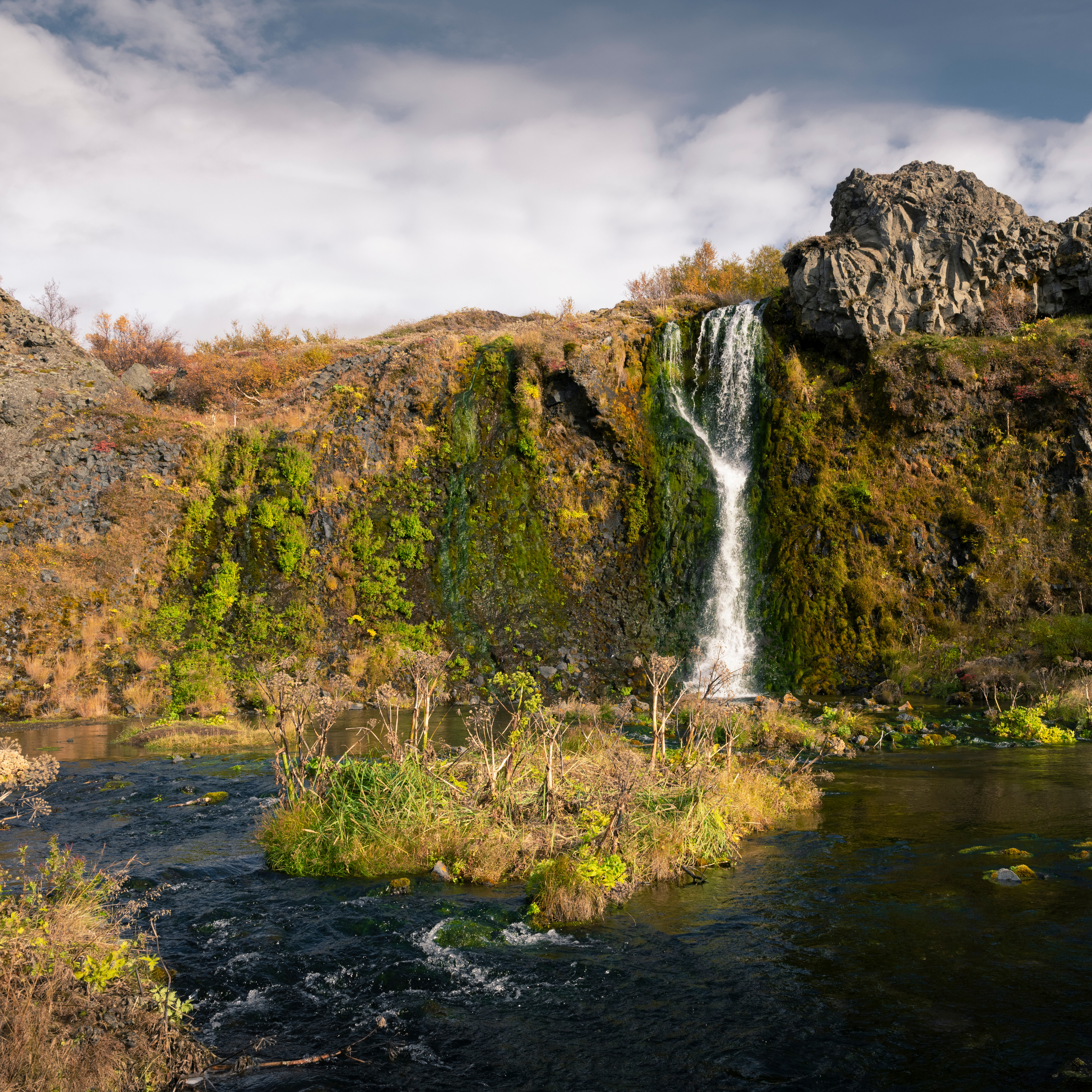 Twin cascades of Hjálparfoss flowing through ancient basalt columns